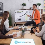 Business owner presenting growth plans on a smart screen to her colleagues at a boardroom table.