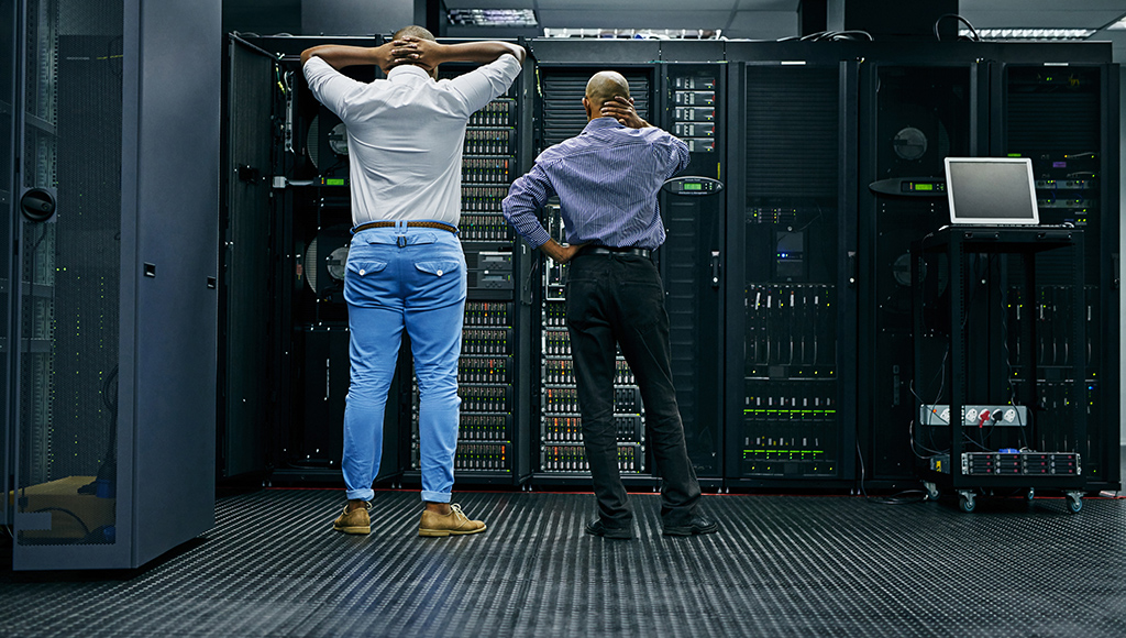 Two IT specialists stare at a server rack during a data loss crisis.