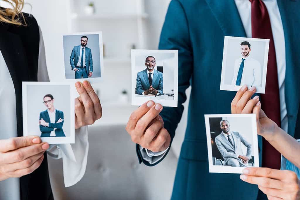 Recruiters at a manufacturing plant hold up images of potential employees.