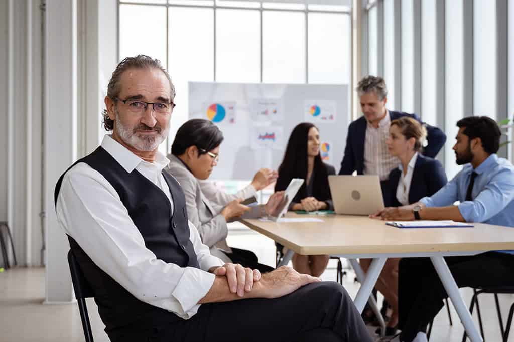 A small business owner smiles in front of a conference table. A small business owner smiles in front of a conference table.