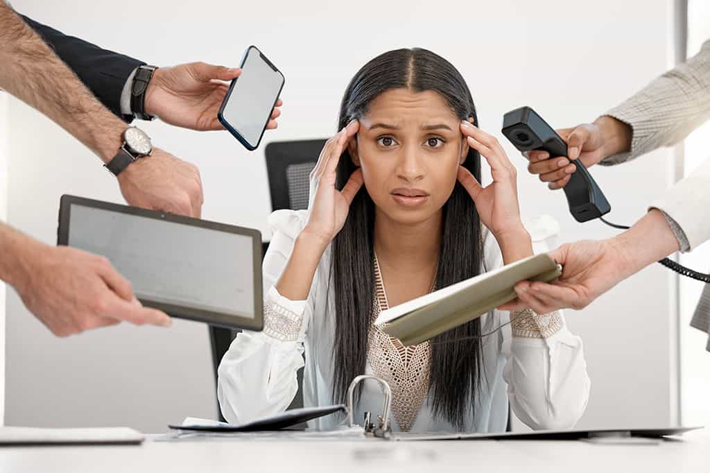 A stressed woman burdened by too many tech tools.