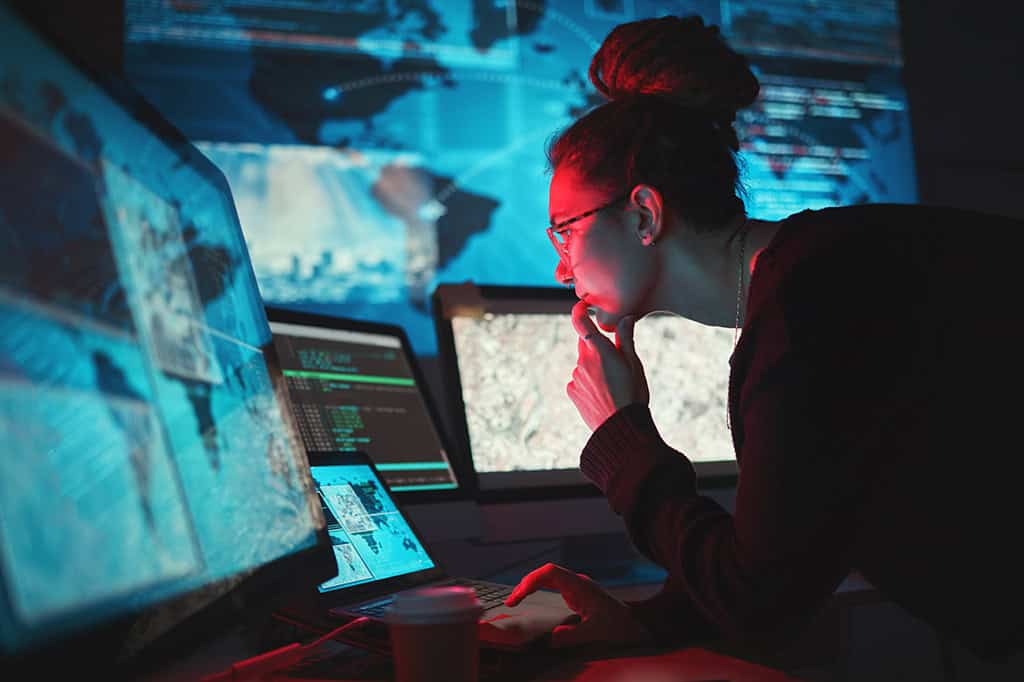 An IT specialists carefully reviews a threat detection display. An IT specialists carefully reviews a threat detection display.