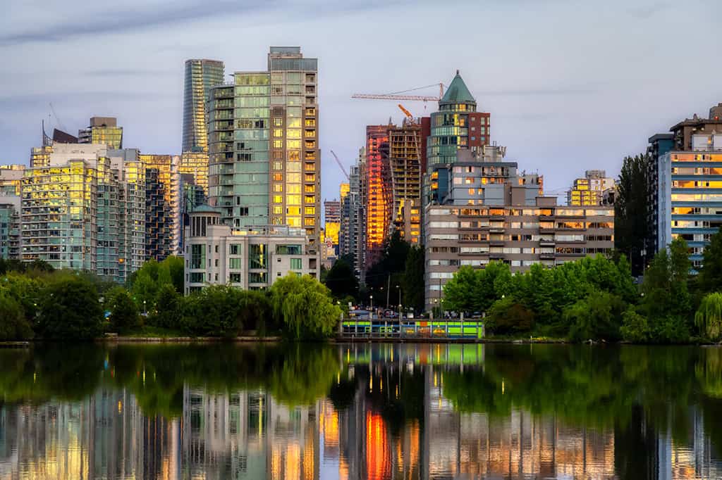 Distant shot of Stanley Park with the skyline and industrial cranes in the background, Vancouver, BC.
