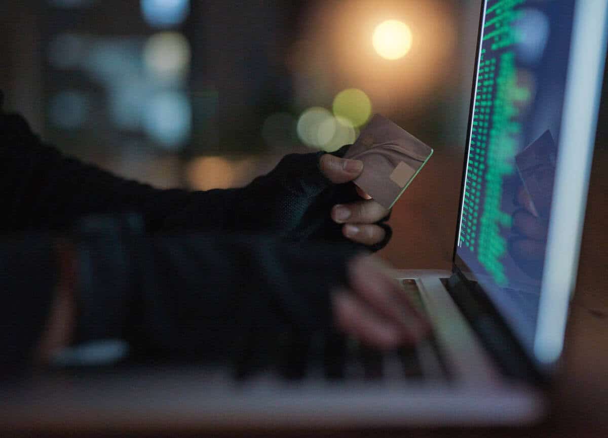 Graphic of person holding credit card up to computer screen to represent ransomware attack and lost revenue